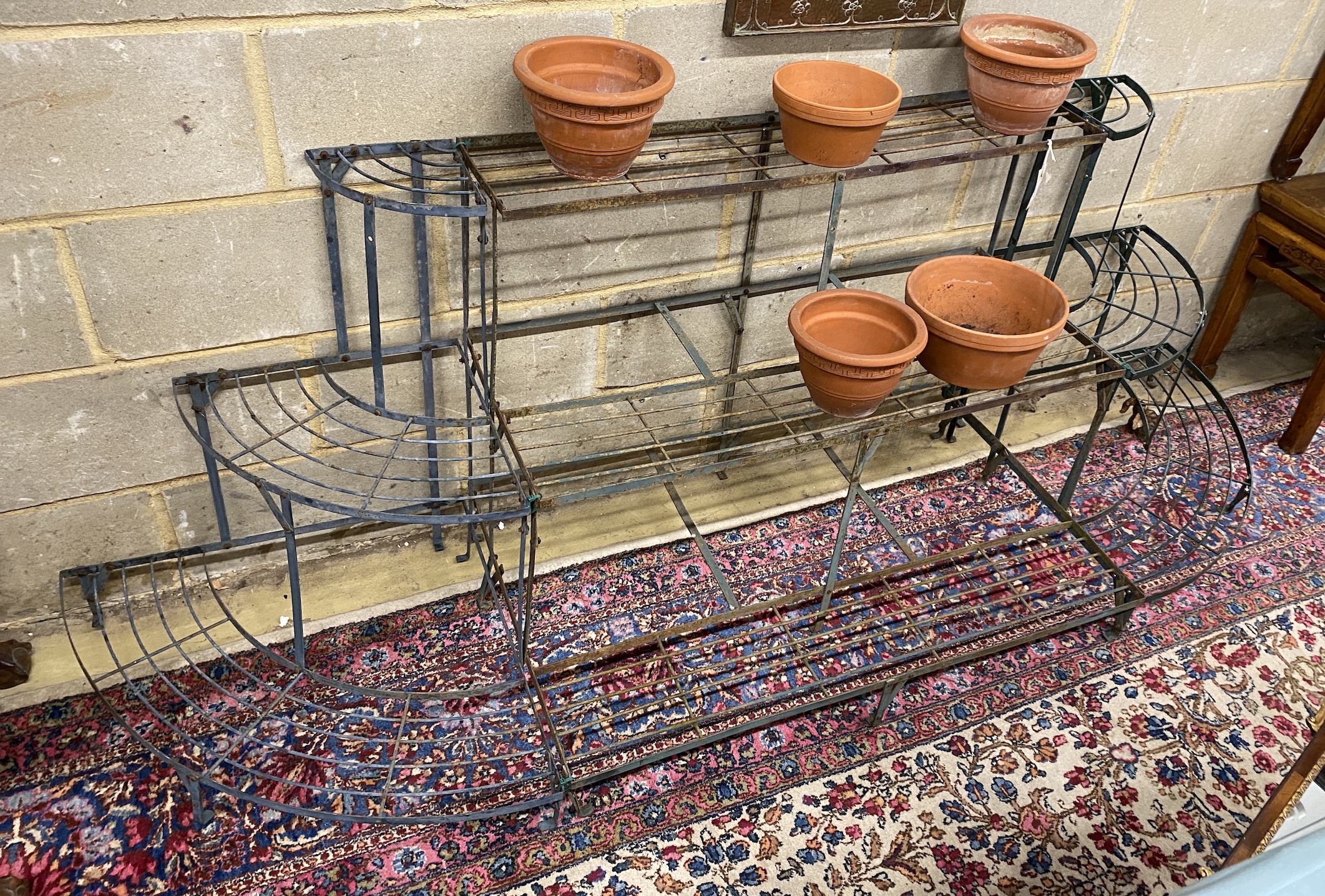 A Victorian style iron 'D' shaped three tier pot stand, width 220cm, depth 60cm, height 73cm together with five terracotta pots